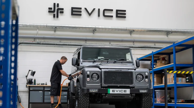 A 4x4 vehicle parked out the front of a building on which the name Evice and the company logo is displayed