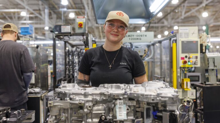 An employee standing behind a hybrid engine part on the shop floor.