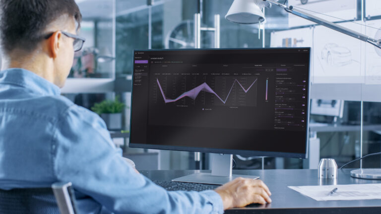 A man sits at a computer screening in an engineering laboratory.