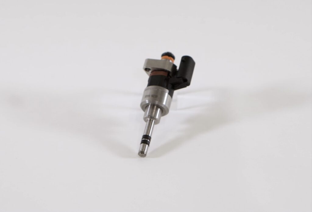 A Dumarey fuel injector on a grey background. 