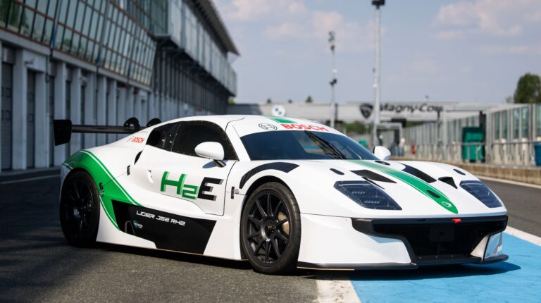 A white and black Ligier JS2 RH2 demonstrator vehicle with a Maserati-Bosch engine is parked on a racetrack.