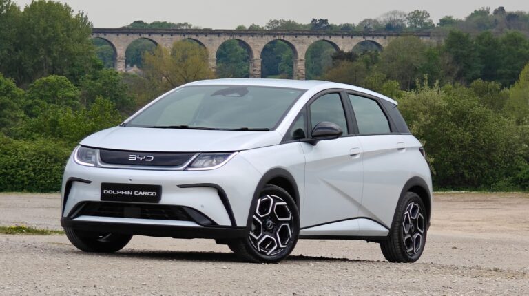 BYD enters UK eLCV market with Dolphin Cargo e-Van The BYD Dolphin Cargo e-Van in a promo pic, with a large stone bridge in the far background.