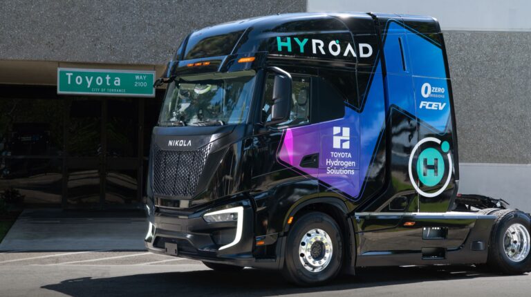 A black Toyota-Hyroad fuel cell truck with purple and green company branding on the cab.