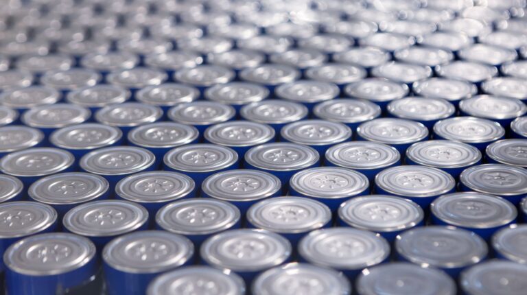 A large number of grey battery cells stacked on their ends.