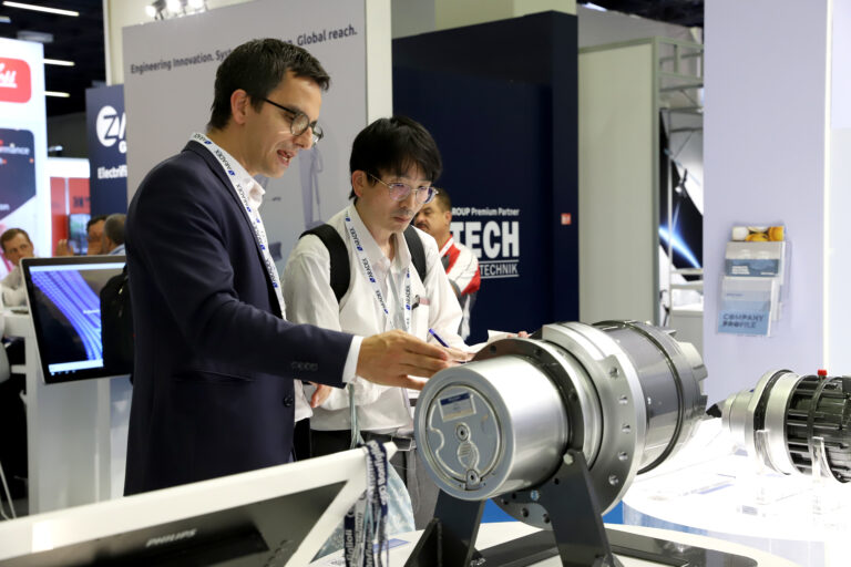 An exhibitor demonstrates a piece of technology at an expo to an interested visitor.